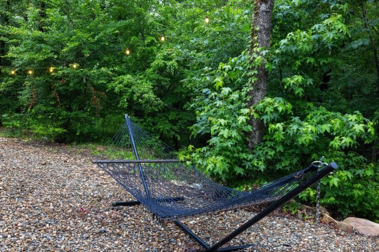 Hammock strung between trees on a gravel pad under string lights