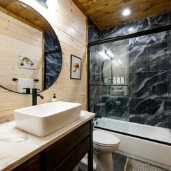 Vanity with a vessel sink and a black tile tub-shower