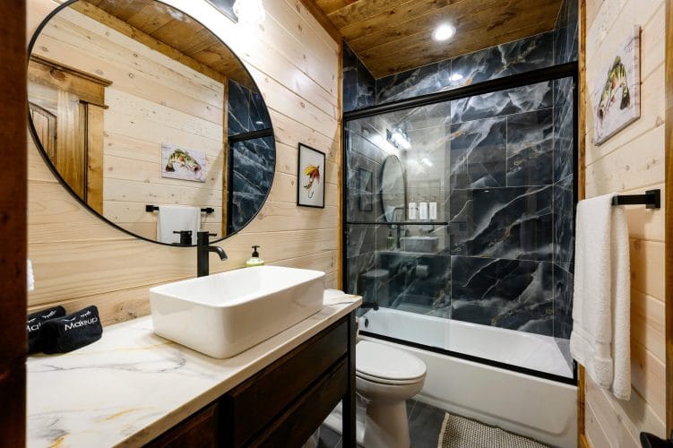 Vanity with a vessel sink and a black tile tub-shower