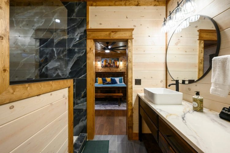 Vanity and shower with a bedroom visible through the doorway