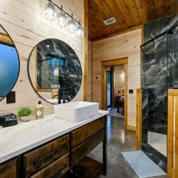 Vessel sinks with round mirrors beside a black tile shower