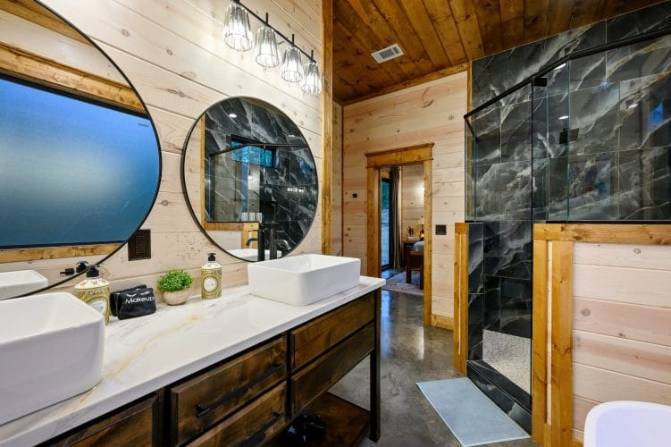Vessel sinks with round mirrors beside a black tile shower