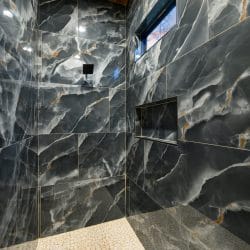 Black marble tile walk-in shower with a niche