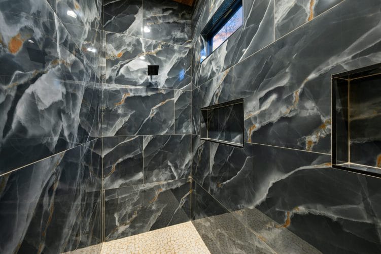 Black marble tile walk-in shower with a niche