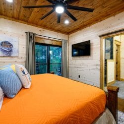 King bed with orange cover, ceiling fan, TV and sliding door