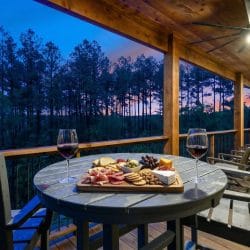 Round table with a charcuterie board and wine on the deck at dusk