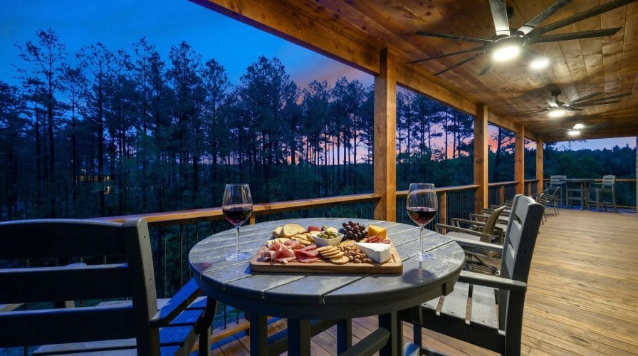 Round table with a charcuterie board and wine on the deck at dusk