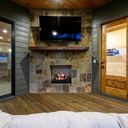 Stone fireplace with a TV on the covered deck, sofa in front