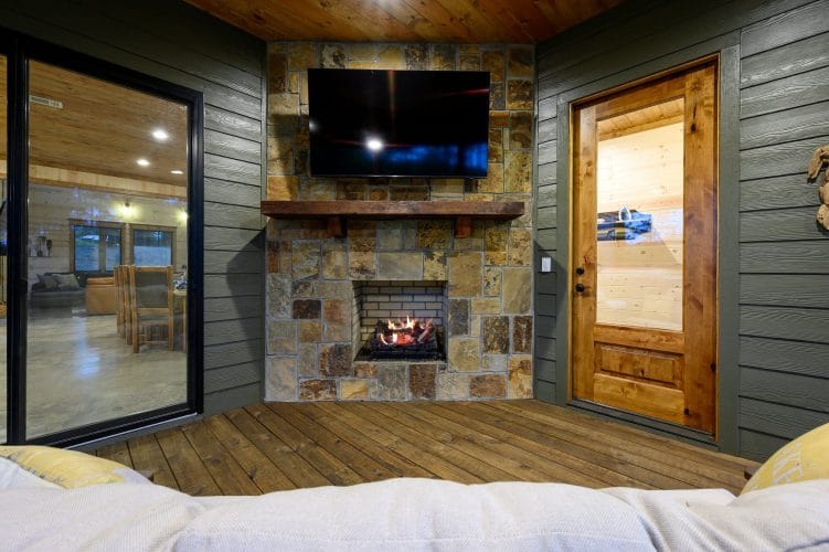 Stone fireplace with a TV on the covered deck, sofa in front