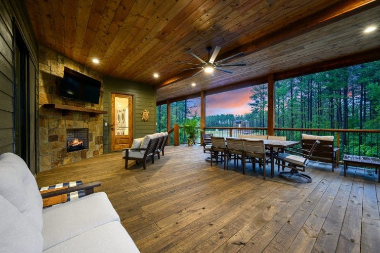Covered deck with a long dining table, fireplace and loungers