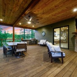 Covered deck with dining table and fireplace, water and trees beyond