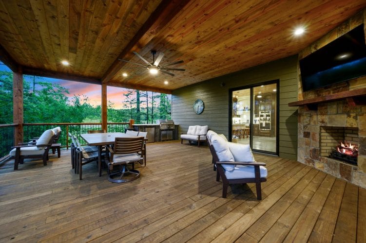 Covered deck with dining table and fireplace, water and trees beyond