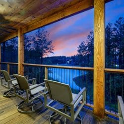 Rocking chairs on a covered deck overlooking the water at dusk