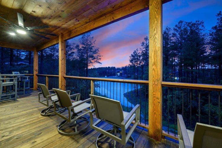 Rocking chairs on a covered deck overlooking the water at dusk