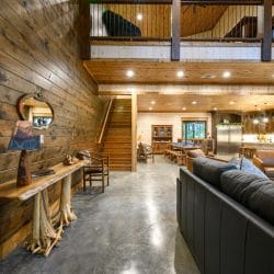 Open main floor with a console table in front, loft above and the kitchen beyond