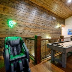 Massage chair beside a shuffleboard table at the loft railing