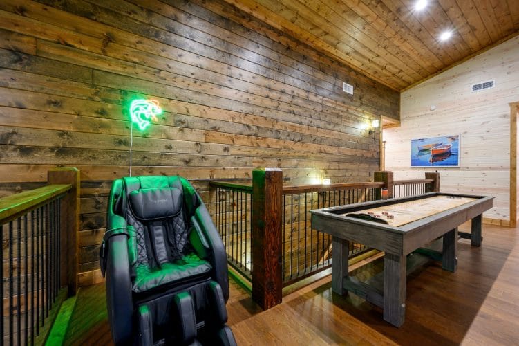 Massage chair beside a shuffleboard table at the loft railing
