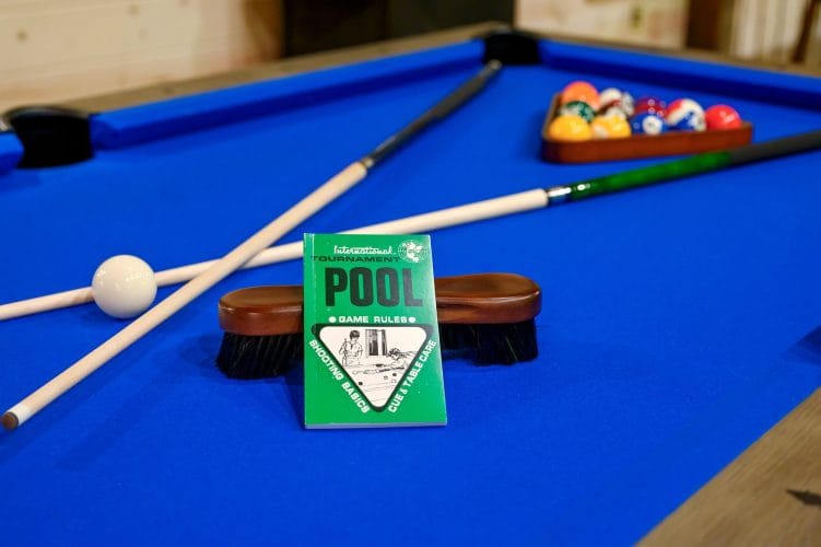 Close view of a blue pool table with cue sticks and balls