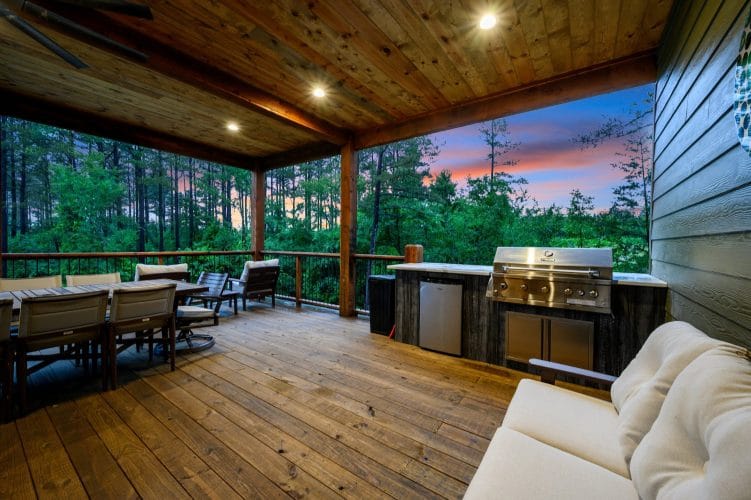 Covered deck with a dining table, built-in grill and sofa