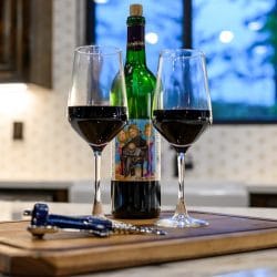 Two glasses of red wine and a bottle on a cutting board