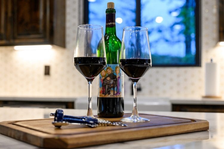 Two glasses of red wine and a bottle on a cutting board