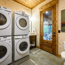 Two stacked washer and dryer sets next to the half bath