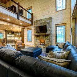 Sectional sofa facing the stone fireplace with the loft railing above