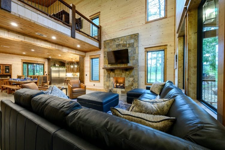 Sectional sofa facing the stone fireplace with the loft railing above