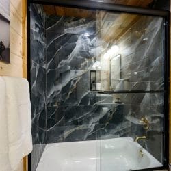 Black marble tub-shower with a glass door