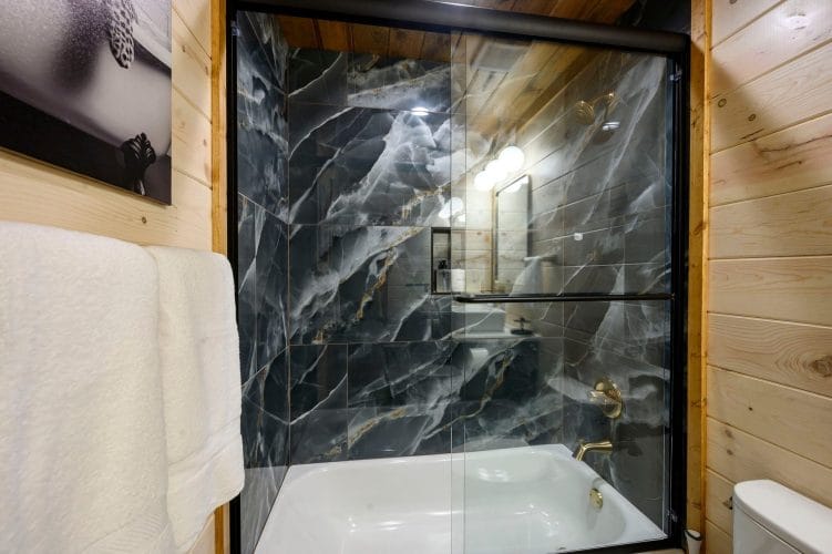 Black marble tub-shower with a glass door