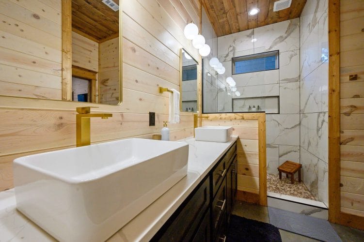 Vessel sink vanity with a marble-look tiled walk-in shower