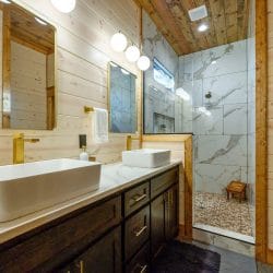 Double vessel-sink vanity next to a marble-look shower