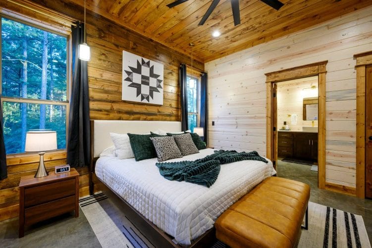King bed with white bedding, green throw and a leather bench at the foot