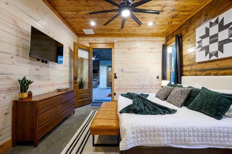 King bedroom with TV, dresser and a doorway to the patio