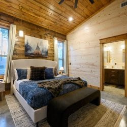 King bed with blue bedding and a black bench at the foot