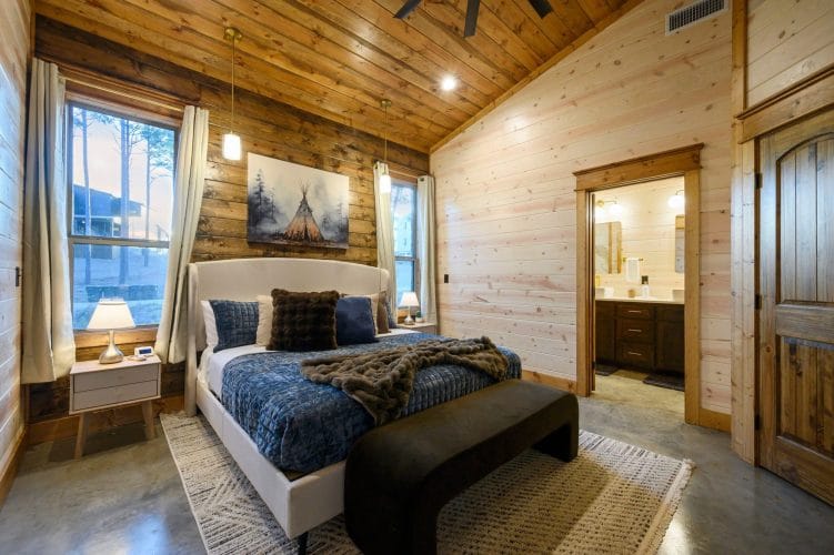 King bed with blue bedding and a black bench at the foot