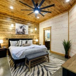 King bed with white bedding and a zebra-print rug under a ceiling fan