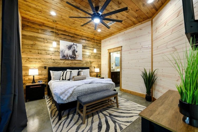 King bed with white bedding and a zebra-print rug under a ceiling fan