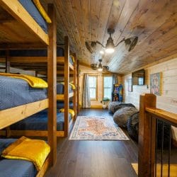 Triple-stacked bunks with navy bedding and bean bag chairs