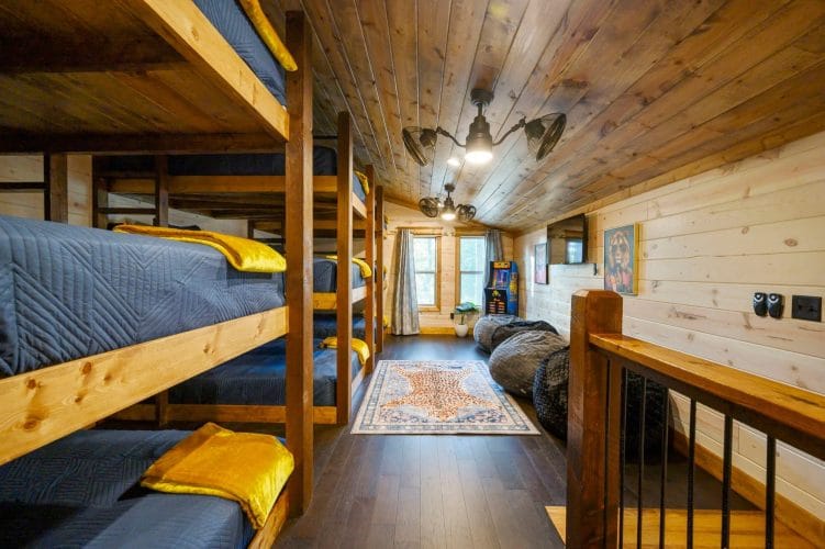 Triple-stacked bunks with navy bedding and bean bag chairs