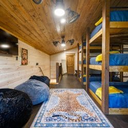 Row of triple-stacked bunks with a wall TV and bean bag chairs