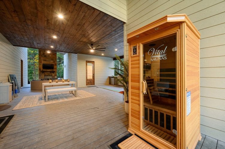 Covered patio with a wood infrared sauna cabin at right and a lounge area behind it