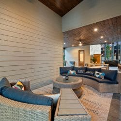 Covered patio with a curved outdoor sofa, wicker chair and dining table