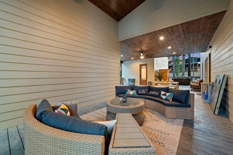 Covered patio with a curved outdoor sofa, wicker chair and dining table