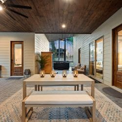 Patio dining table with a bench, cornhole boards and seating beyond