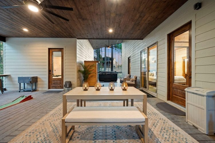 Patio dining table with a bench, cornhole boards and seating beyond