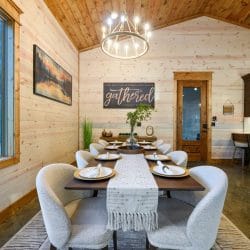 Dining table set for a meal with a framed 'gathered' sign behind it