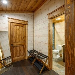 Landing outside the bunk room with luggage racks, a mirror and a bathroom doorway