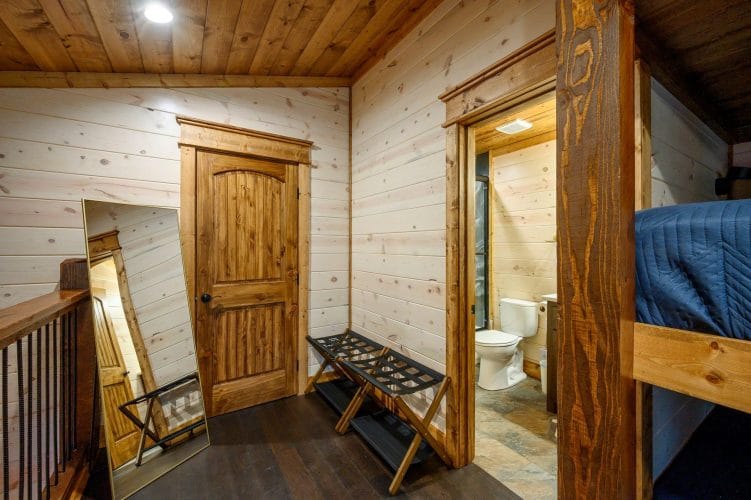Landing outside the bunk room with luggage racks, a mirror and a bathroom doorway