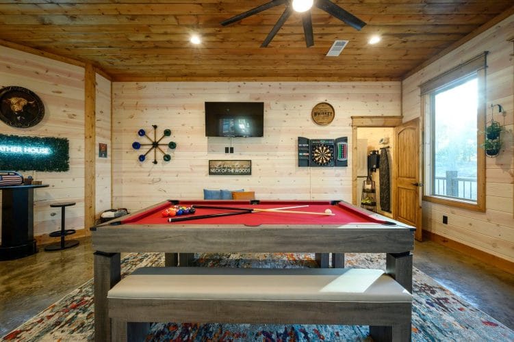 Red-felt pool table with a dartboard and TV on the wall behind